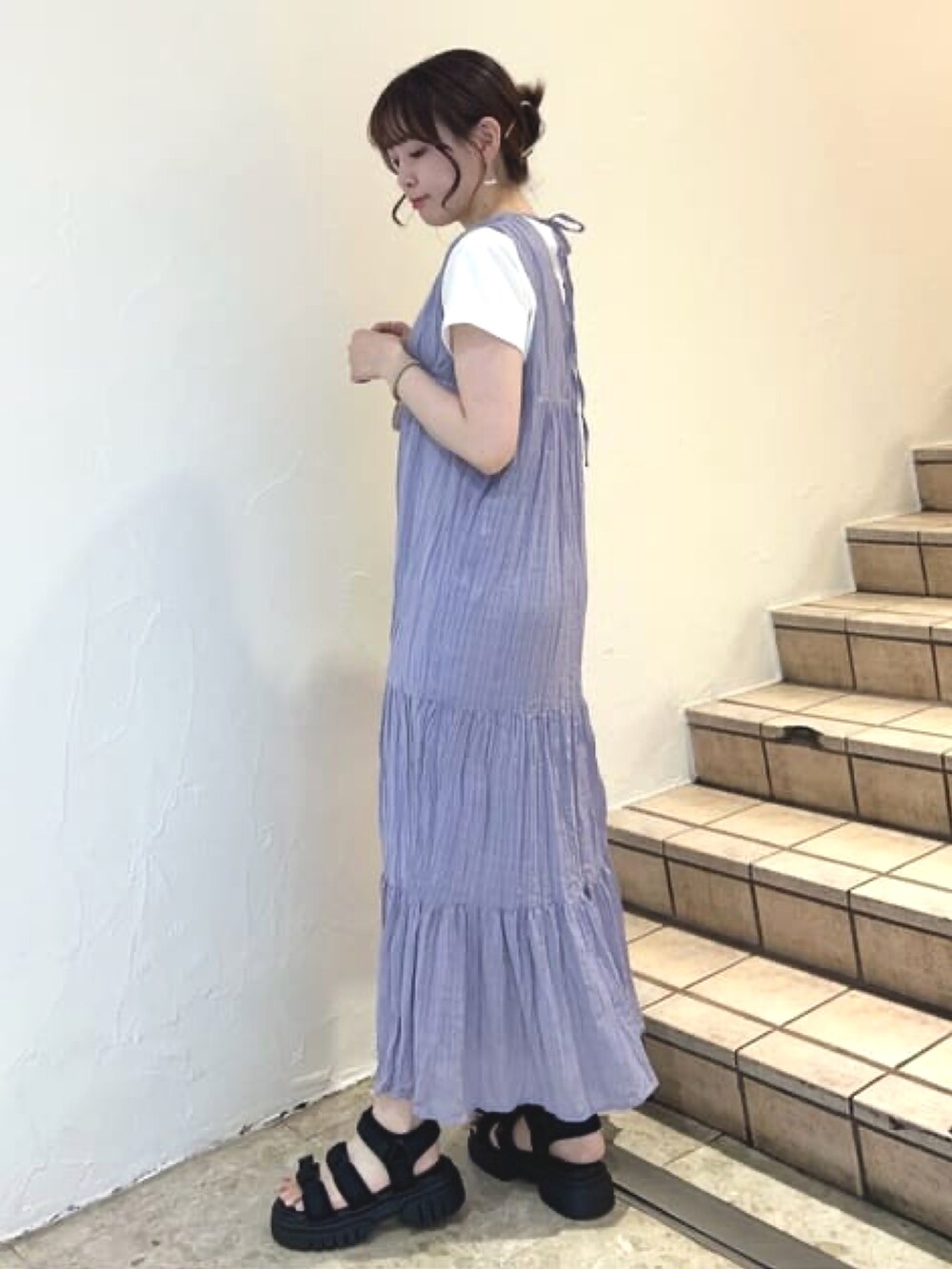 パープル系のワンピース、ホワイト系のTシャツ/カットソー、ブラック系のサンダルを着用したレディースの夏コーディネートの2枚目の写真