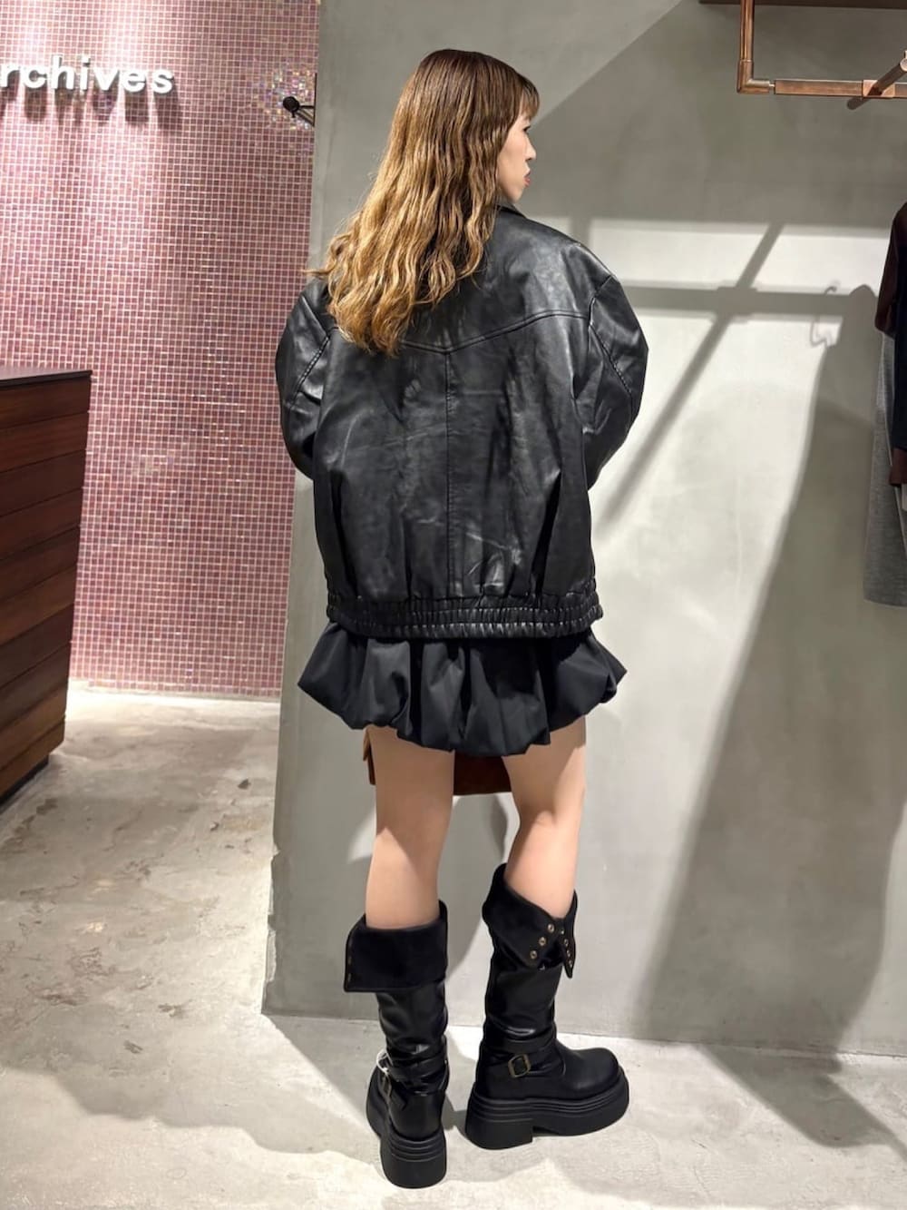 ブラック系のブルゾン、ベージュ系のTシャツ/カットソー、ブラック系のスカートを着用したレディースの秋コーディネートの3枚目の写真