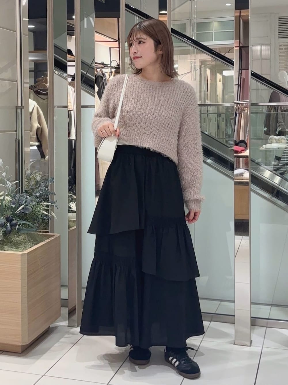 ホワイト系のニット/セーター、ホワイト系のチェスターコート、ブラック系のスカートを着用したレディースの冬コーディネートの2枚目の写真