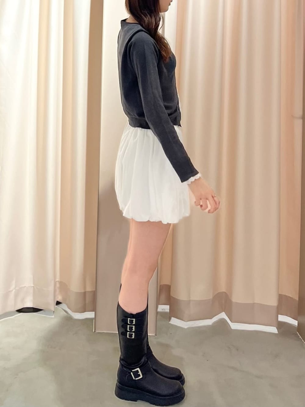 グレー系のニット/セーター、ホワイト系のスカートを着用したレディースの春コーディネートの2枚目の写真