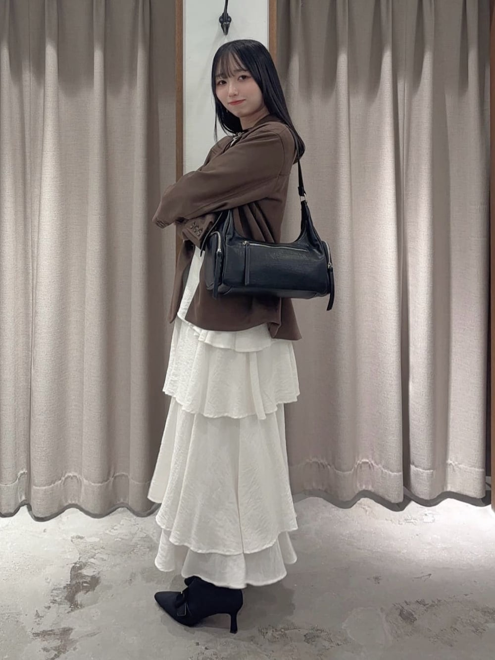 ブラウン系のテーラードジャケット、ブラック系のスカート、ブラック系のハンドバッグを着用したレディースの秋コーディネートの2枚目の写真