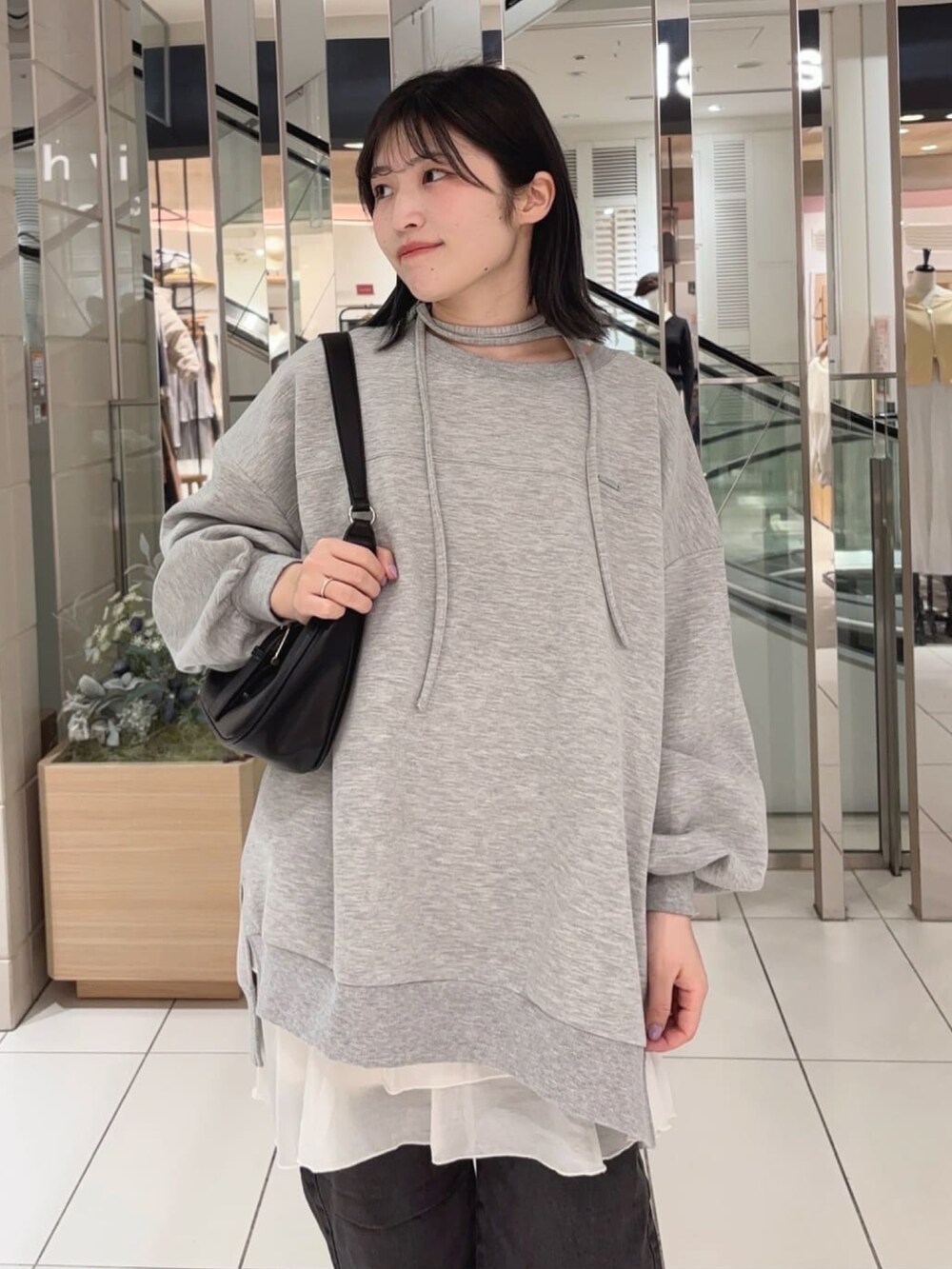 グレー系のスウェット、ホワイト系のスカート、ブラック系のデニムパンツを着用したレディースの冬コーディネートの3枚目の写真