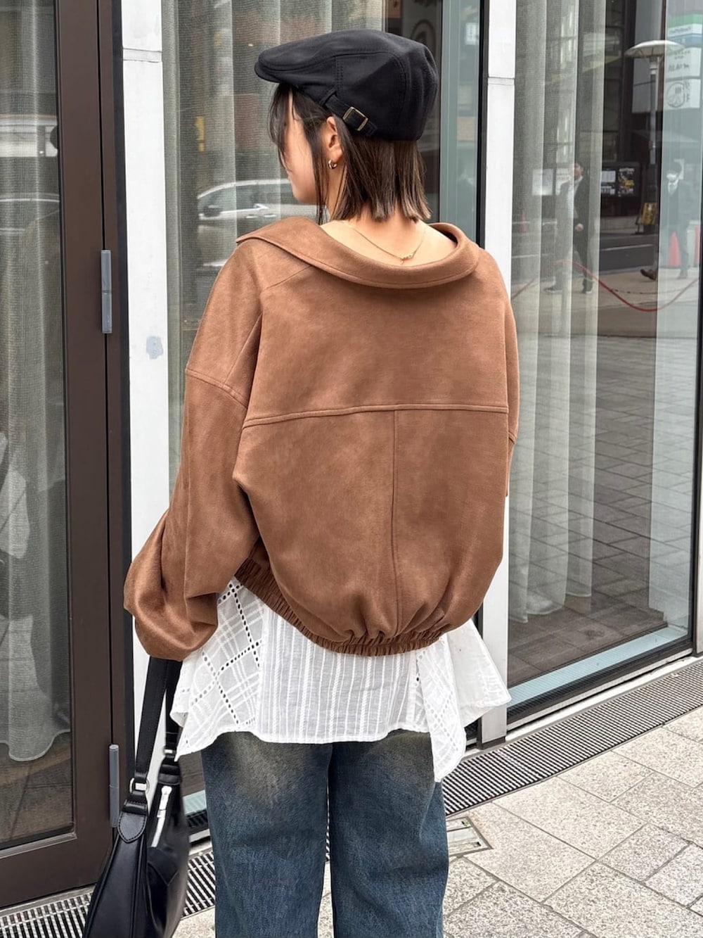 ブラウン系のブルゾン、ホワイト系のワンピース、ブルー系のデニムパンツを着用したレディースの春コーディネートの4枚目の写真