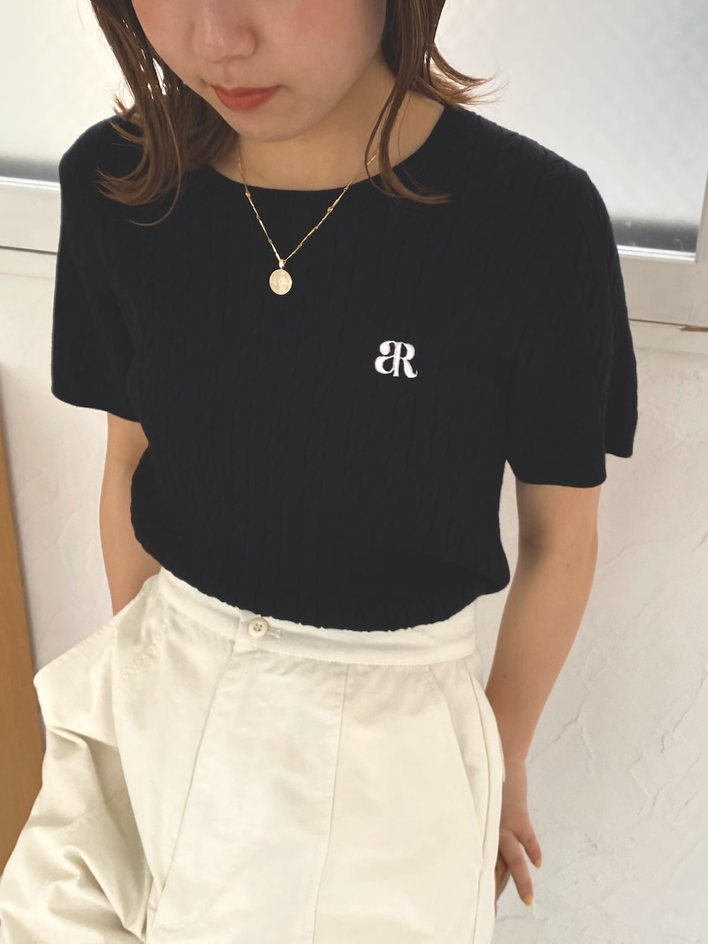 ブラック系のニット/セーター、ホワイト系のカーゴパンツ、ブラック系のサンダルを着用したレディースの春コーディネートの2枚目の写真