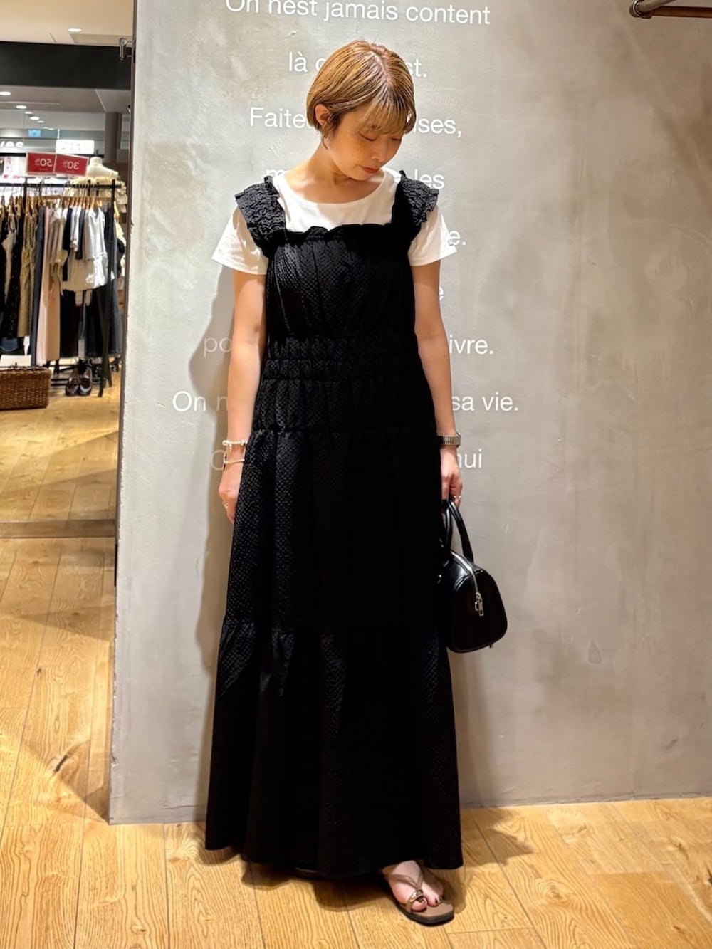 ブラック系のワンピース、ブラック系のボストンバッグ、ブラウン系のサンダルを着用したレディースの夏コーディネートの2枚目の写真