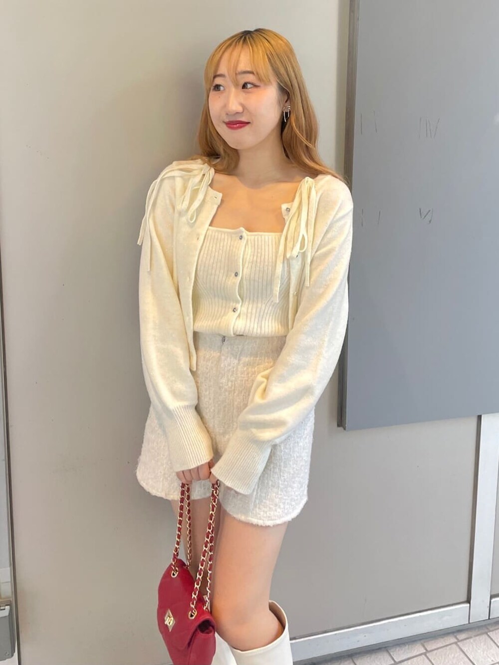 ホワイト系のニット/セーター、ホワイト系のその他パンツ、レッド系のショルダーバッグを着用したレディースの冬コーディネートの3枚目の写真