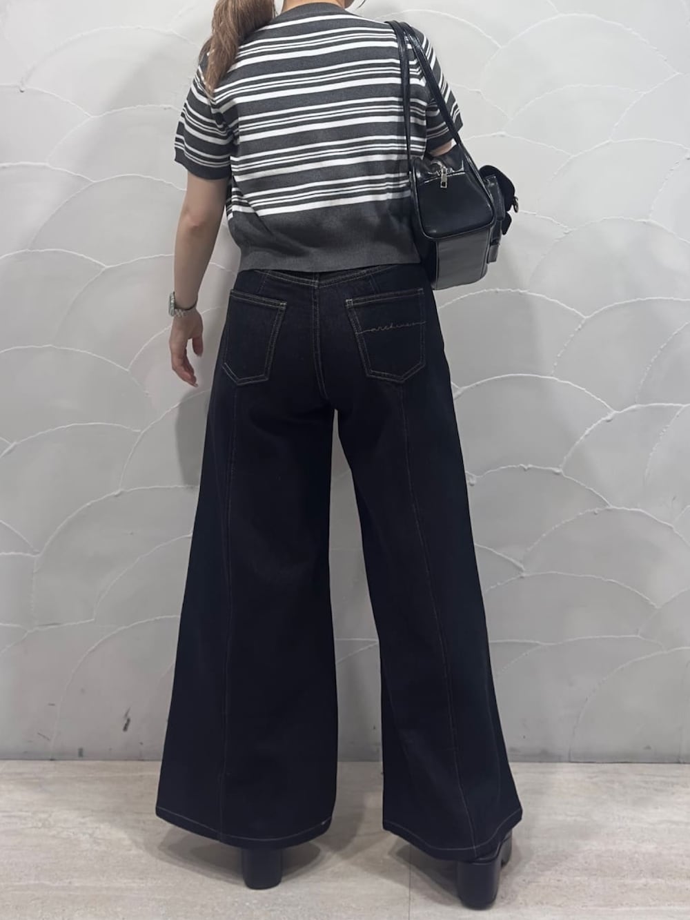 ブラック系のデニムパンツ、ブラック系のサンダル、ホワイト系のキャミソールを着用したレディースの夏コーディネートの2枚目の写真