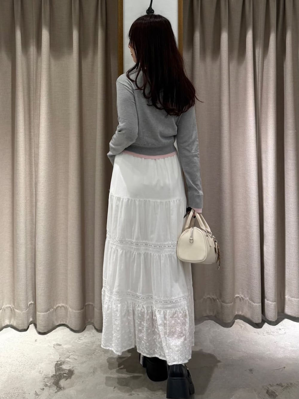 グレー系のカーディガン/ボレロ、ホワイト系のスカートを着用したレディースの春コーディネートの3枚目の写真