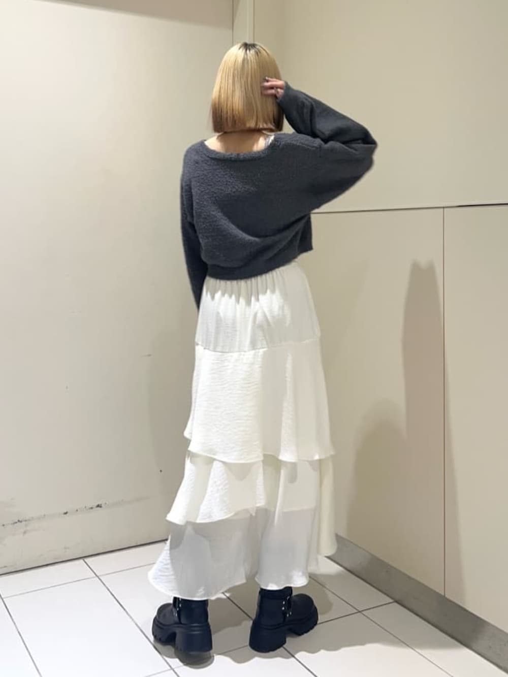 ホワイト系のスカート、グレー系のニット/セーター、ブラック系のショルダーバッグを着用したレディースの冬コーディネートの2枚目の写真