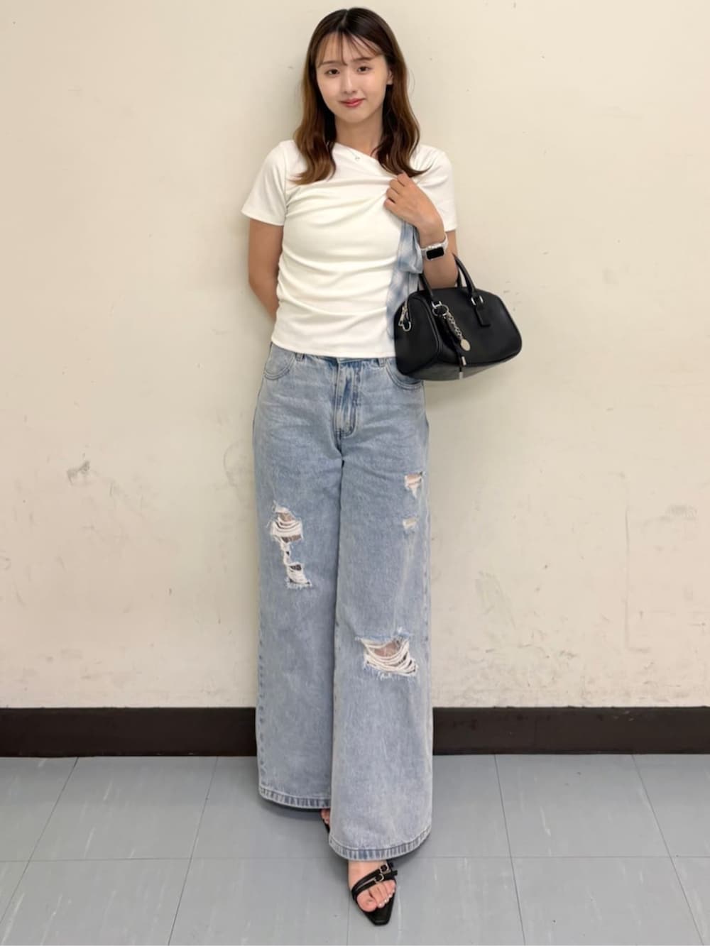 ブルー系のデニムパンツ、ブラック系のサンダル、ホワイト系のTシャツ/カットソーを着用したレディースの夏コーディネートの3枚目の写真