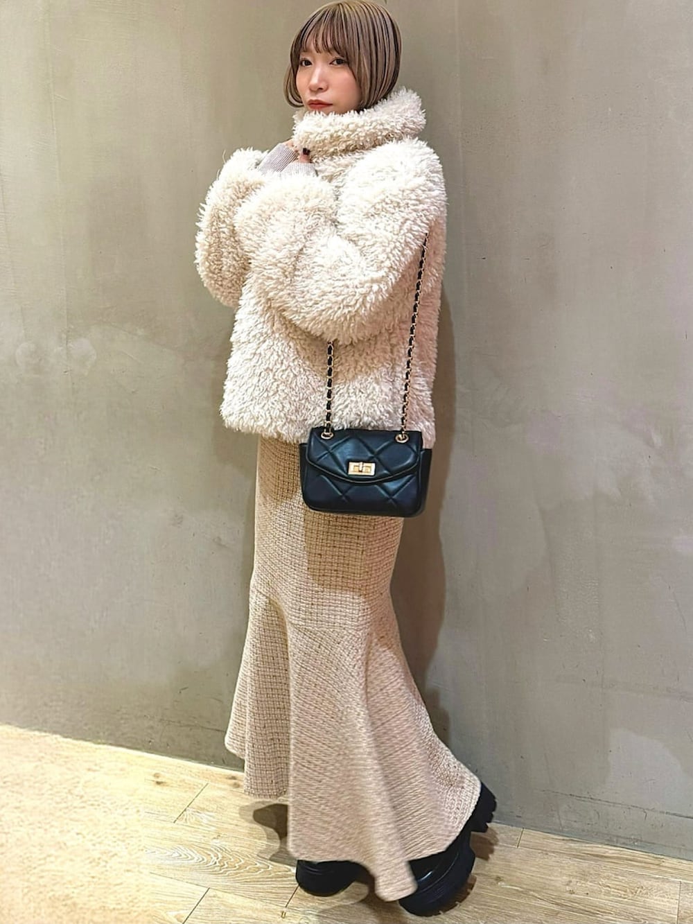 ピンク系のニット/セーター、ベージュ系のスカート、ブラック系のショルダーバッグを着用したレディースの冬コーディネートの3枚目の写真