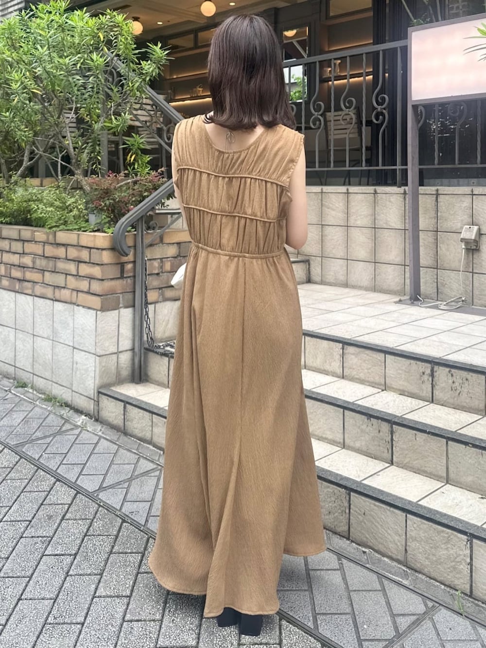 ブラウン系のワンピース、ブラック系のサンダル、ホワイト系のハンドバッグを着用したレディースの夏コーディネートの2枚目の写真