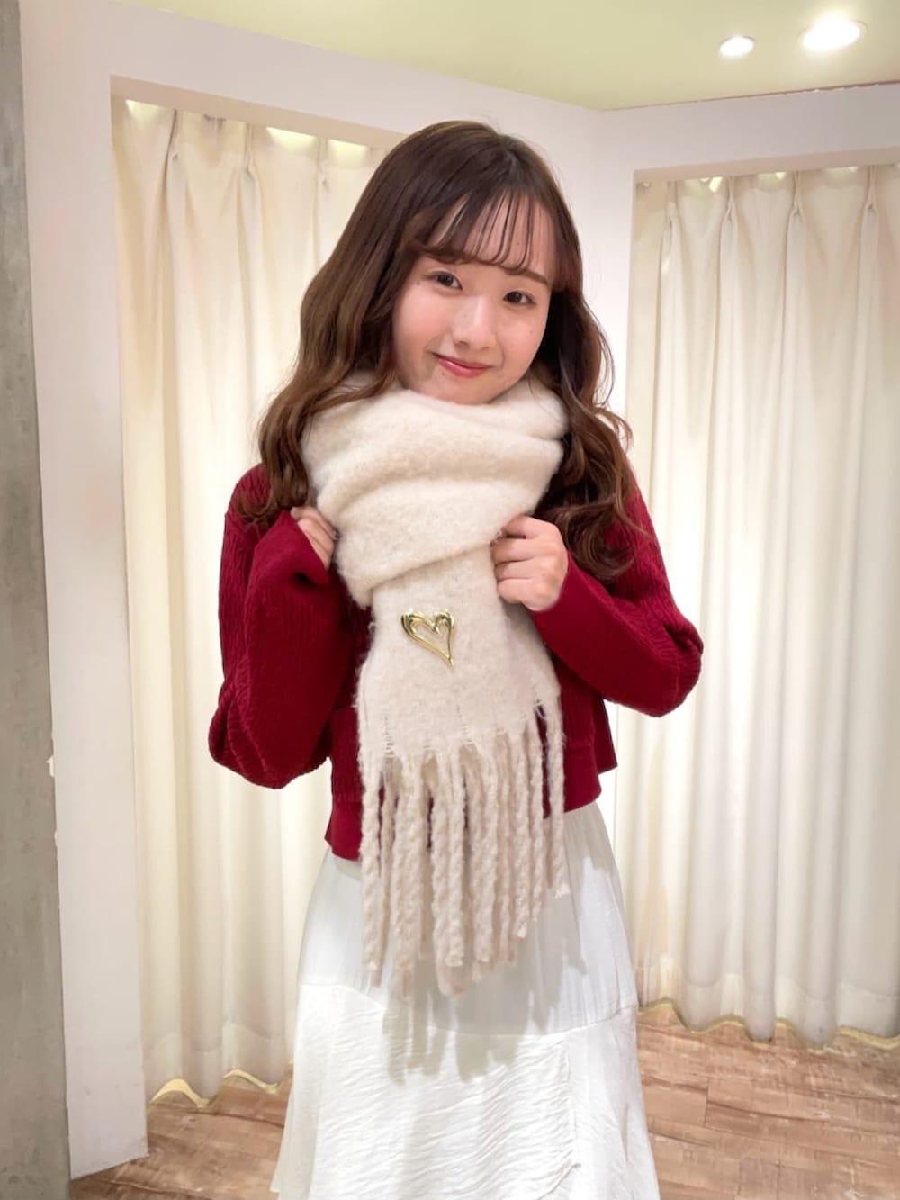 レッド系のニット/セーター、ホワイト系のスカート、ホワイト系のマフラーを着用したレディースの冬コーディネートの3枚目の写真