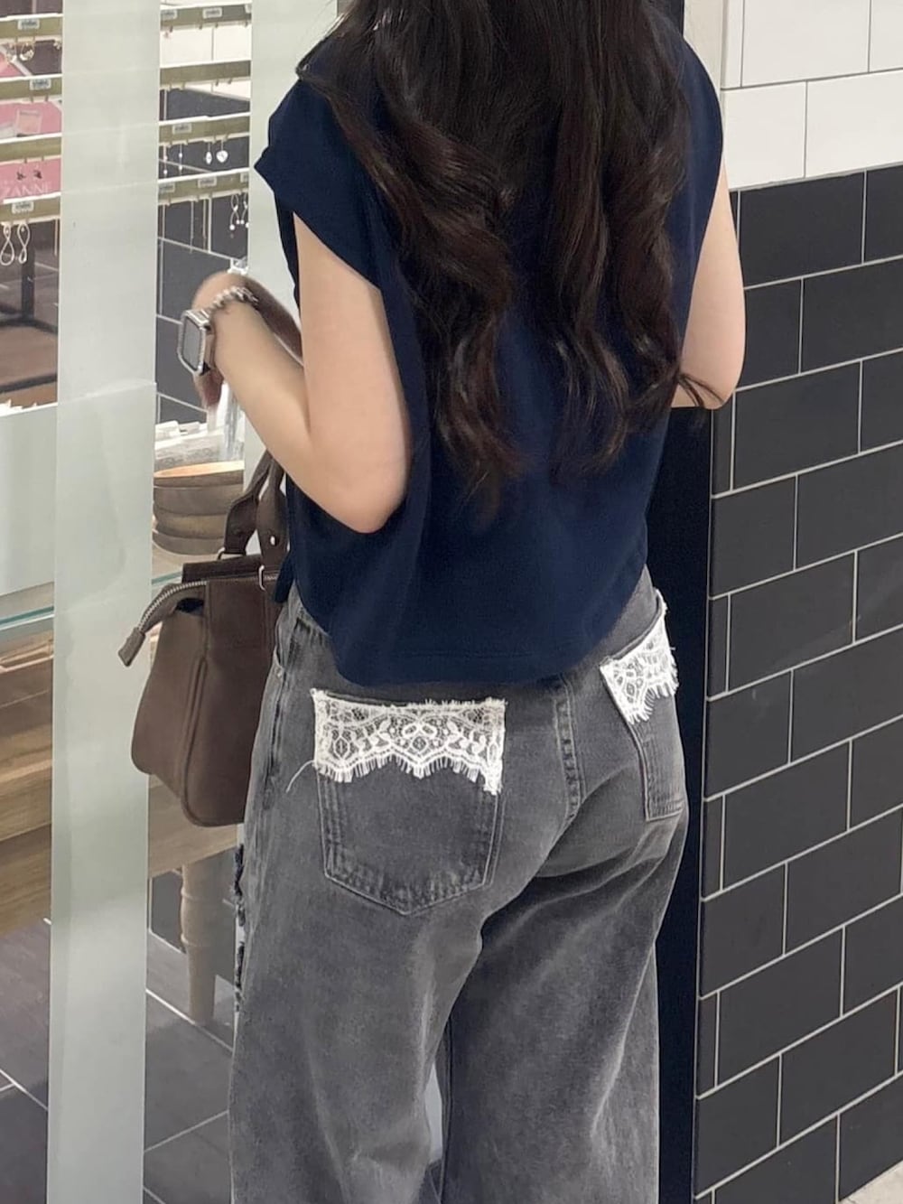 ブルー系のスウェット、グレー系のデニムパンツ、ブラウン系のショルダーバッグを着用したレディースの夏コーディネートの3枚目の写真