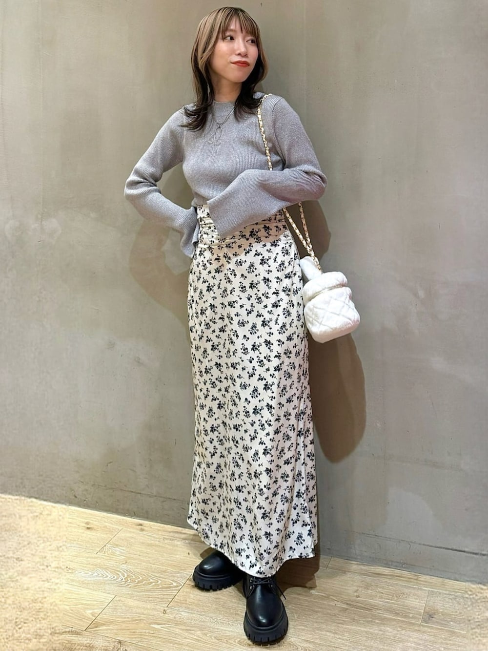 ホワイト系のショルダーバッグ、ホワイト系のスカート、ブラック系のニット/セーターを着用したレディースの冬コーディネートの2枚目の写真