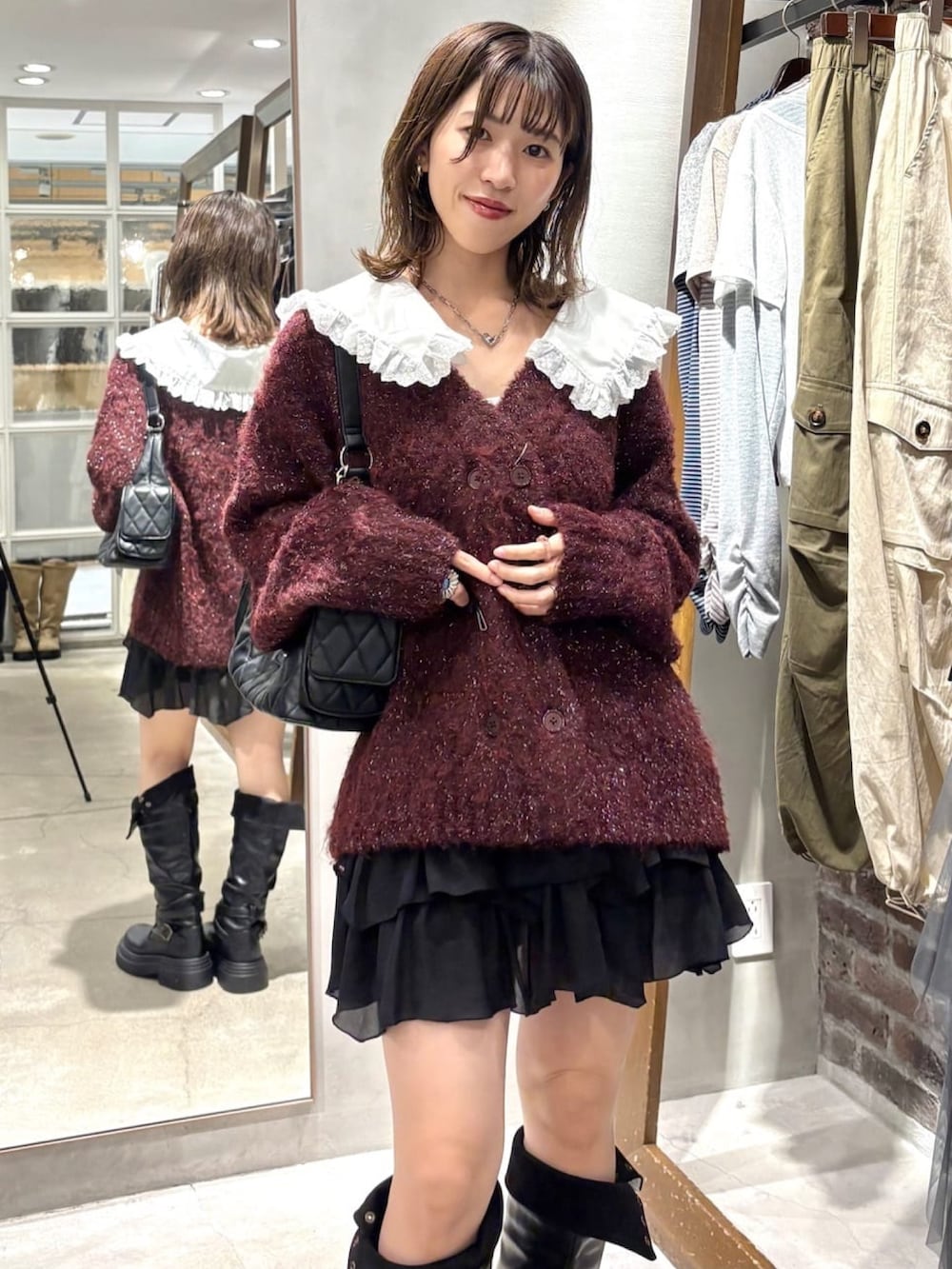 ブラック系のスカート、ブラック系のブーツ、レッド系のカーディガン/ボレロを着用したレディースの秋コーディネートの4枚目の写真