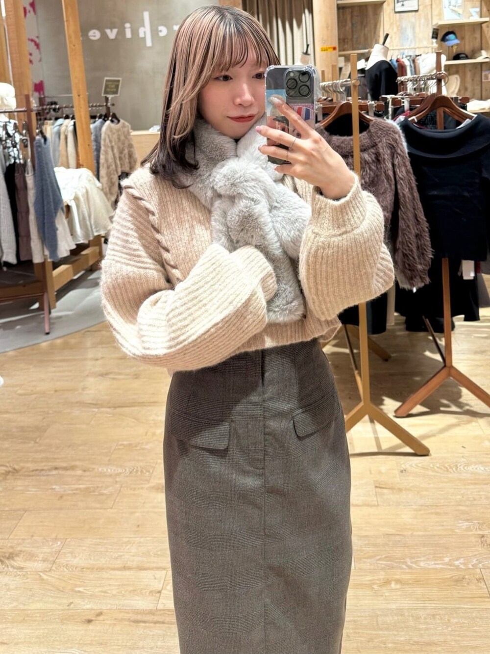 ブラック系のスカート、ホワイト系のニット/セーター、グレー系のマフラーを着用したレディースの冬コーディネートの2枚目の写真