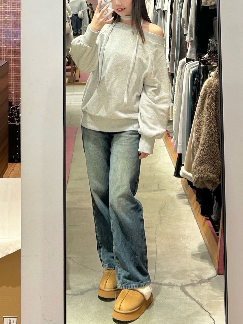 ブルー系のデニムパンツ、グレー系のスウェット、イエロー系のショルダーバッグを着用したレディースの冬コーディネートの2枚目の写真