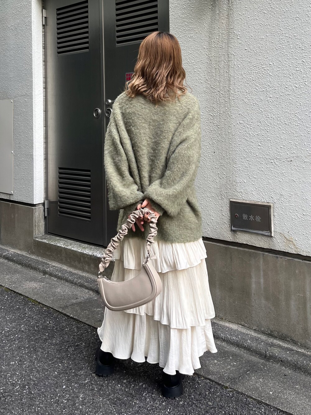 グリーン系のニット/セーター、ブラック系のブーツを着用したレディースの秋コーディネートの2枚目の写真