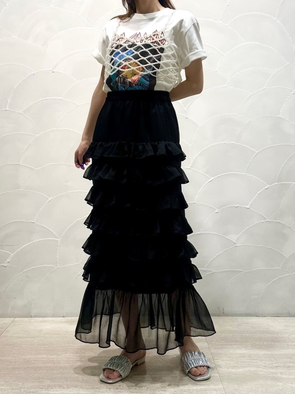 ベージュ系のベスト、ブラック系のスカート、ゴールド系のサンダルを着用したレディースの夏コーディネートの2枚目の写真