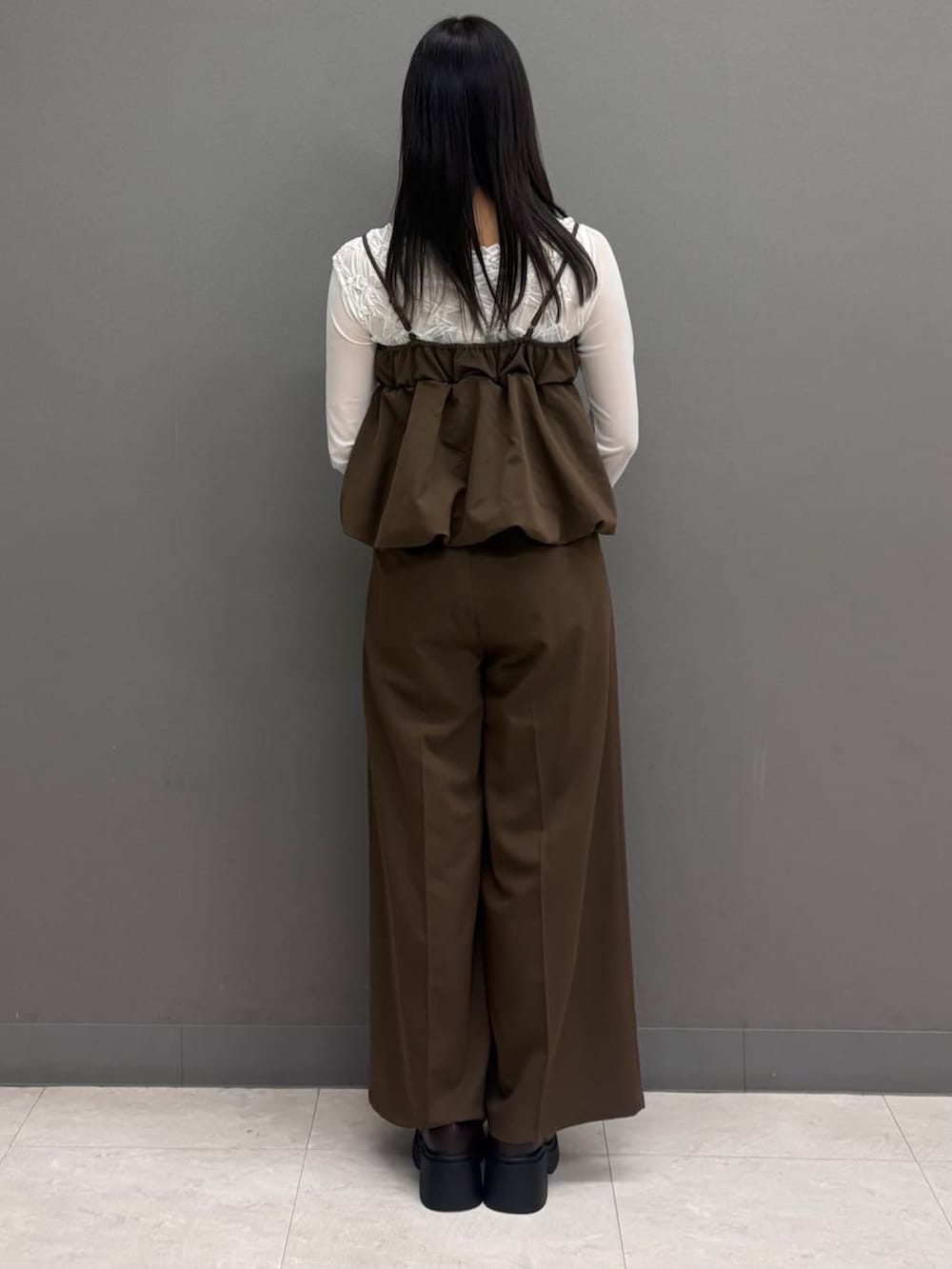 ブルー系のパンツドレス、ホワイト系のTシャツ/カットソー、ブラック系のボストンバッグを着用したレディースの秋コーディネートの3枚目の写真