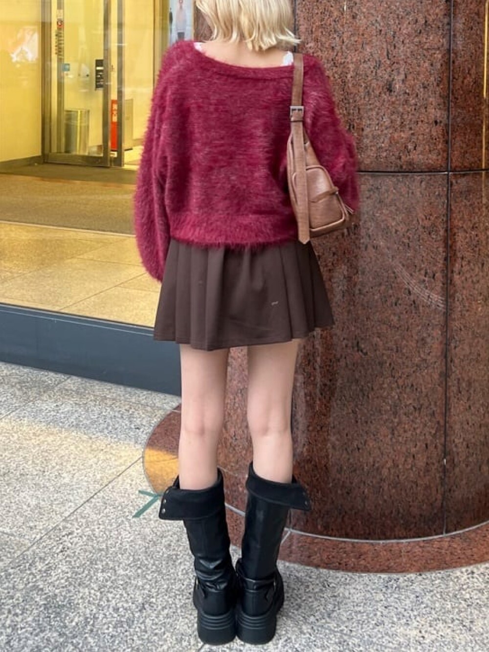 レッド系のカーディガン/ボレロ、ブラウン系のスカート、ブラック系のブーツを着用したレディースの秋コーディネートの3枚目の写真