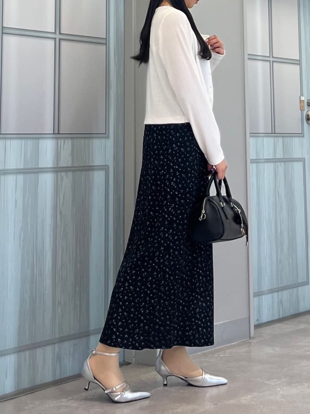 グレー系のカーディガン/ボレロ、ブラック系のワンピース、グレー系のパンプスを着用したレディースの春コーディネートの2枚目の写真