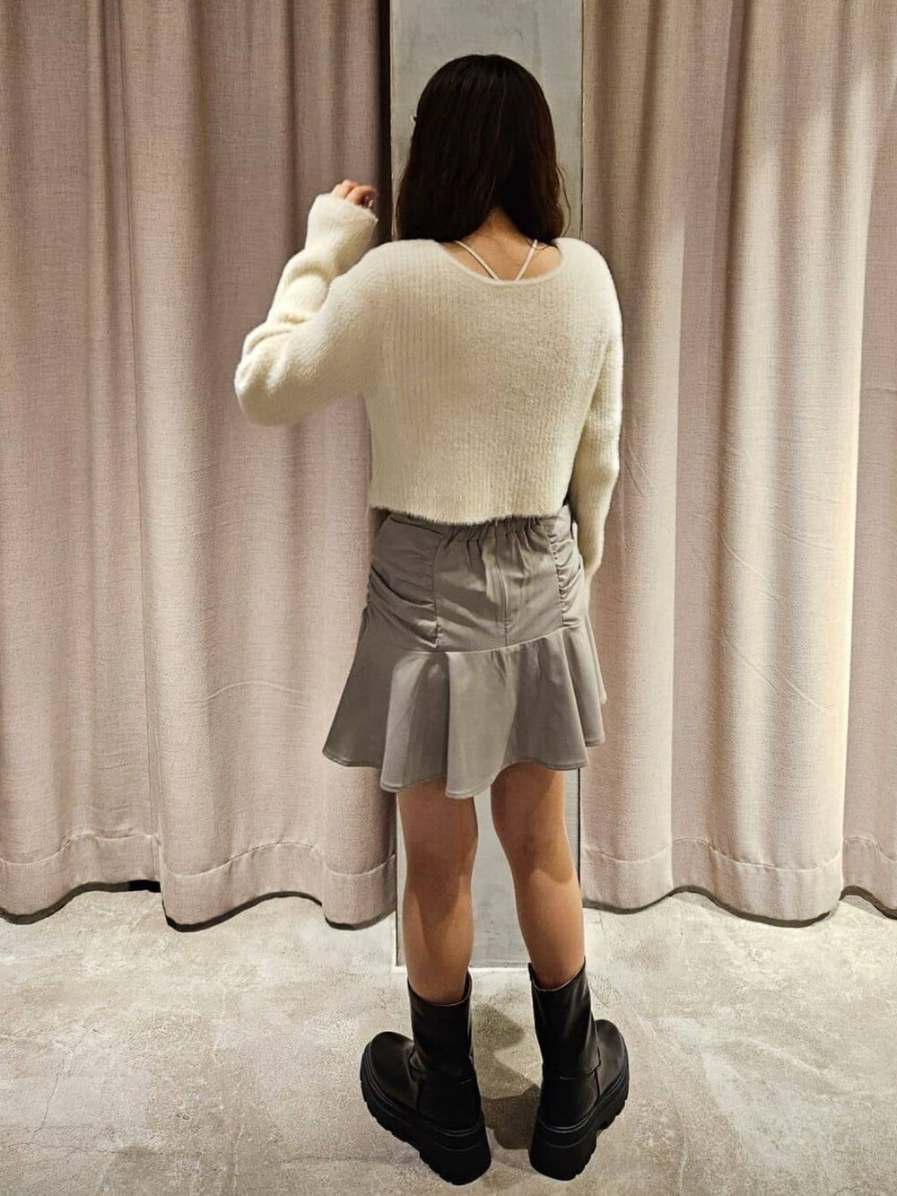 ホワイト系のニット/セーター、グレー系のスカート、ブラウン系のブーツを着用したレディースの冬コーディネートの2枚目の写真