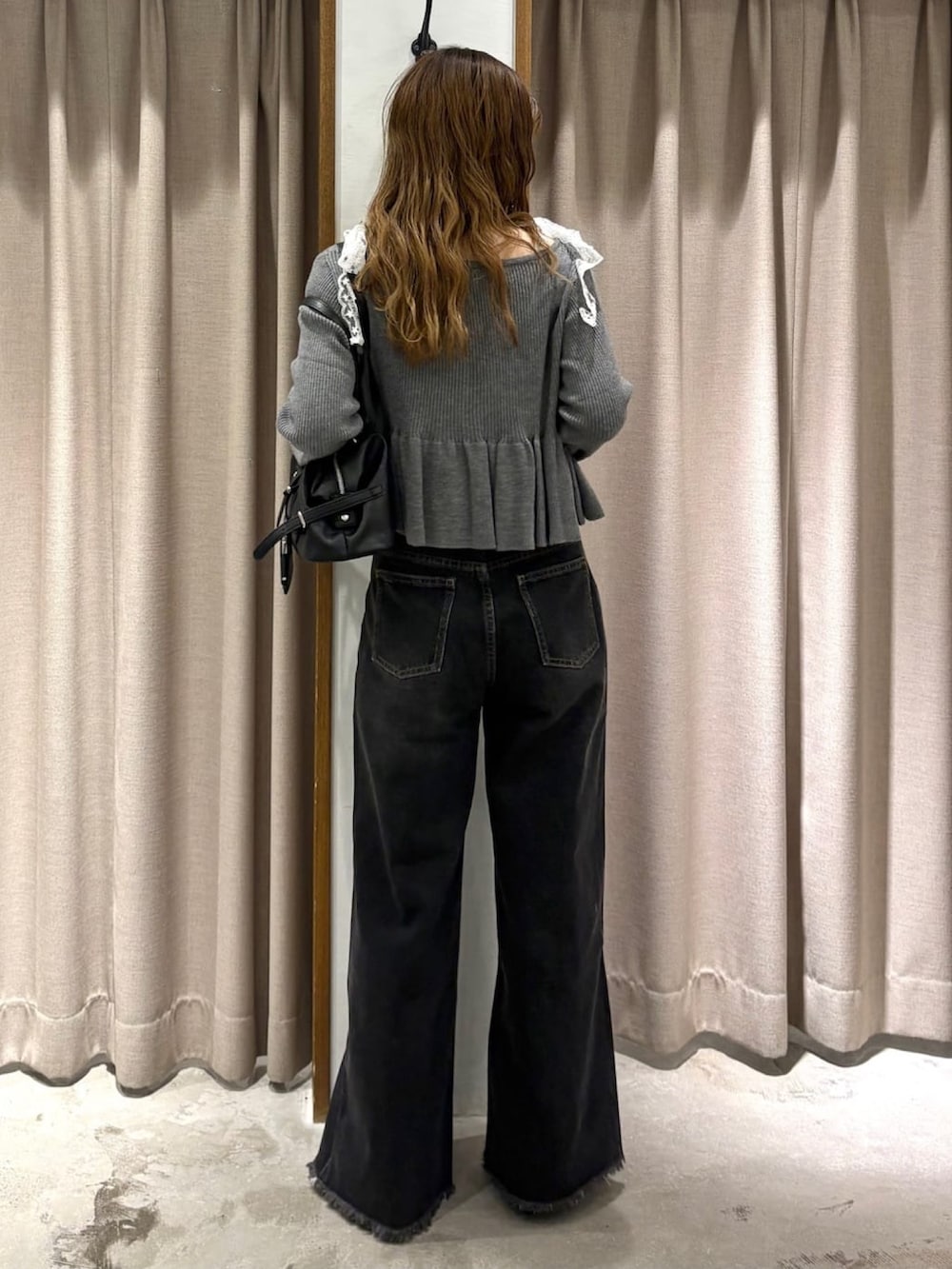 ブラック系のデニムパンツ、ブラック系のパンプス、グレー系のアンサンブルを着用したレディースの秋コーディネートの3枚目の写真