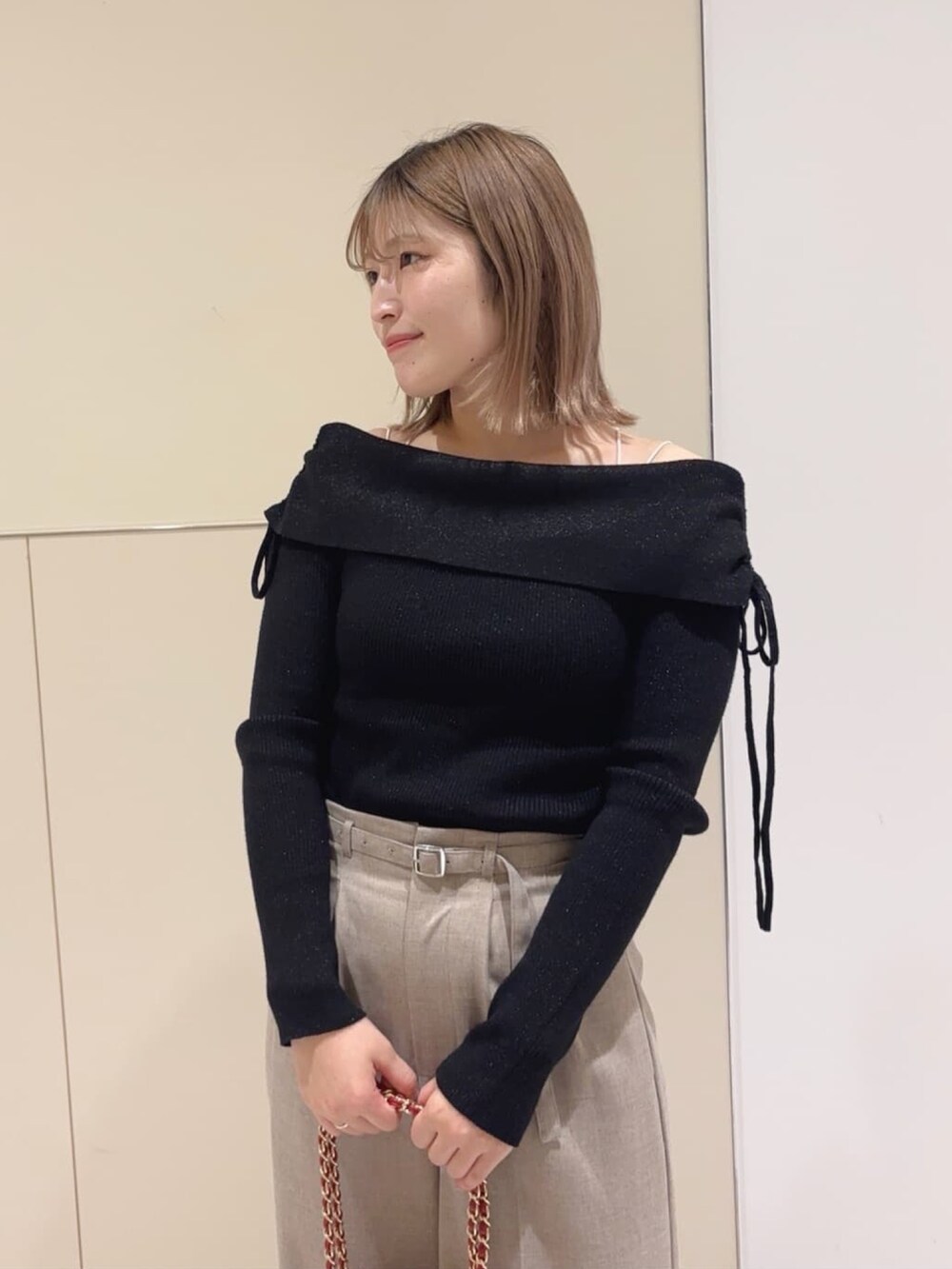 ブラック系のニット/セーター、ベージュ系のスラックス、レッド系のショルダーバッグを着用したレディースの冬コーディネートの3枚目の写真