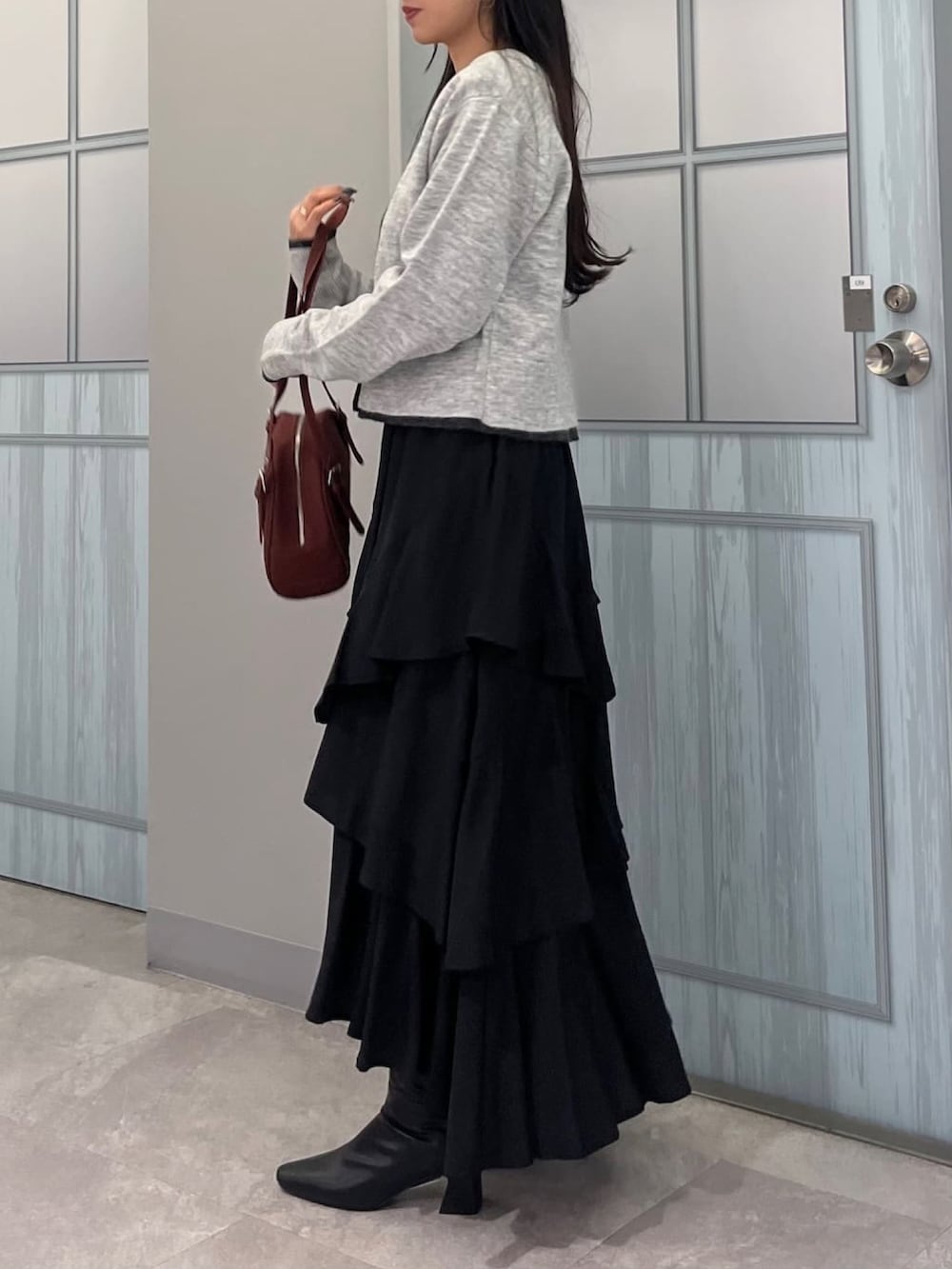 グレー系のアンサンブル、ブラック系のスカートを着用したレディースの秋コーディネートの2枚目の写真