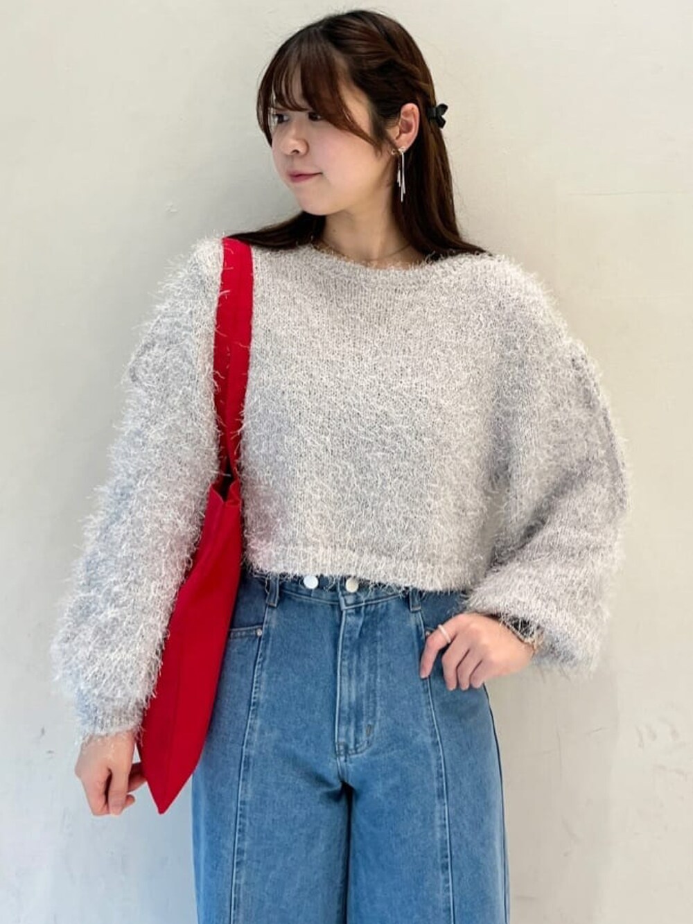 グレー系のニット/セーター、ブルー系のデニムパンツ、レッド系のトートバッグを着用したレディースの冬コーディネートの3枚目の写真