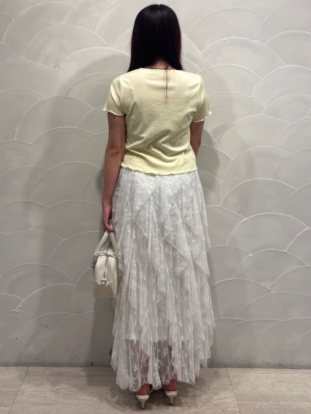 イエロー系のTシャツ/カットソー、ホワイト系のスカート、ホワイト系のボストンバッグを着用したレディースの夏コーディネートの3枚目の写真