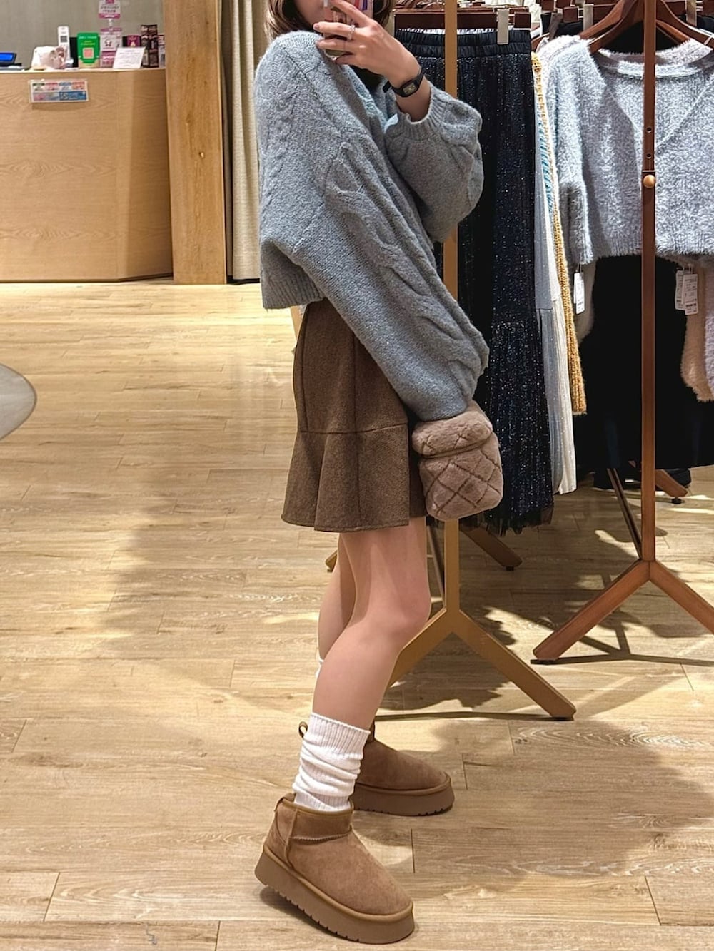 グリーン系のニット/セーター、ブラウン系のスカート、ベージュ系のショルダーバッグを着用したレディースの冬コーディネートの2枚目の写真