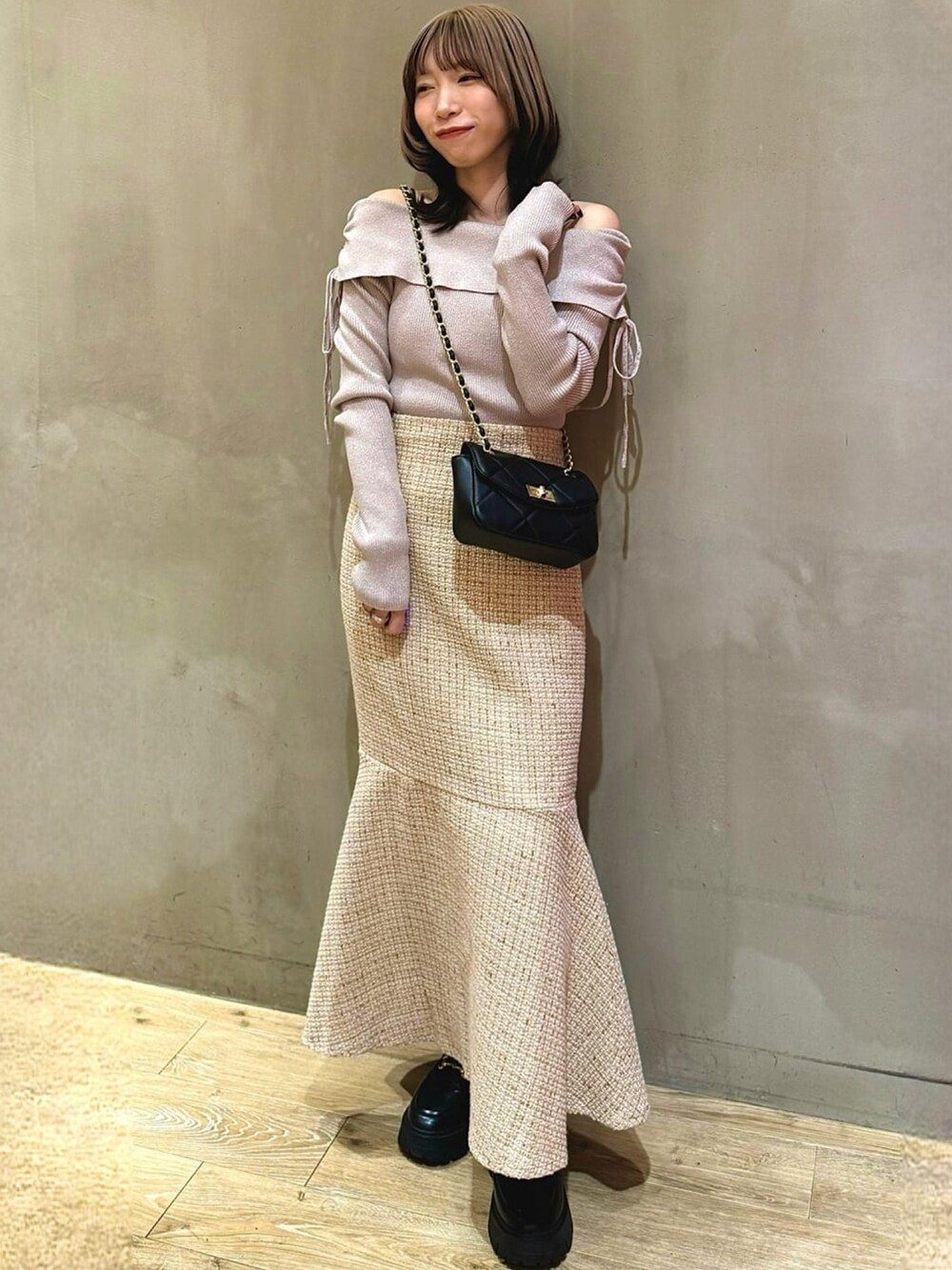 ピンク系のニット/セーター、ベージュ系のスカート、ブラック系のショルダーバッグを着用したレディースの冬コーディネートの2枚目の写真