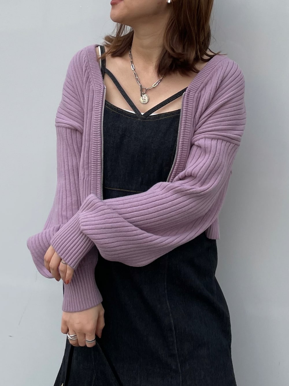 ブラック系のワンピース、ブラック系のハンドバッグ、パープル系のカーディガン/ボレロを着用したレディースの冬コーディネートの2枚目の写真