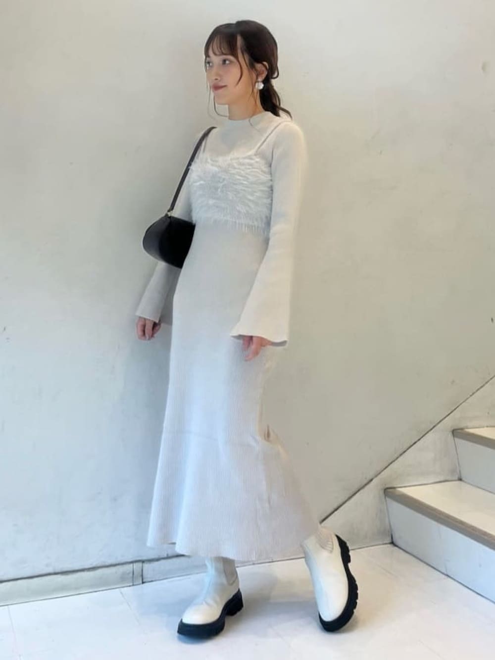 ホワイト系のワンピース、ブラウン系のショルダーバッグ、ホワイト系のブーツを着用したレディースの冬コーディネートの2枚目の写真