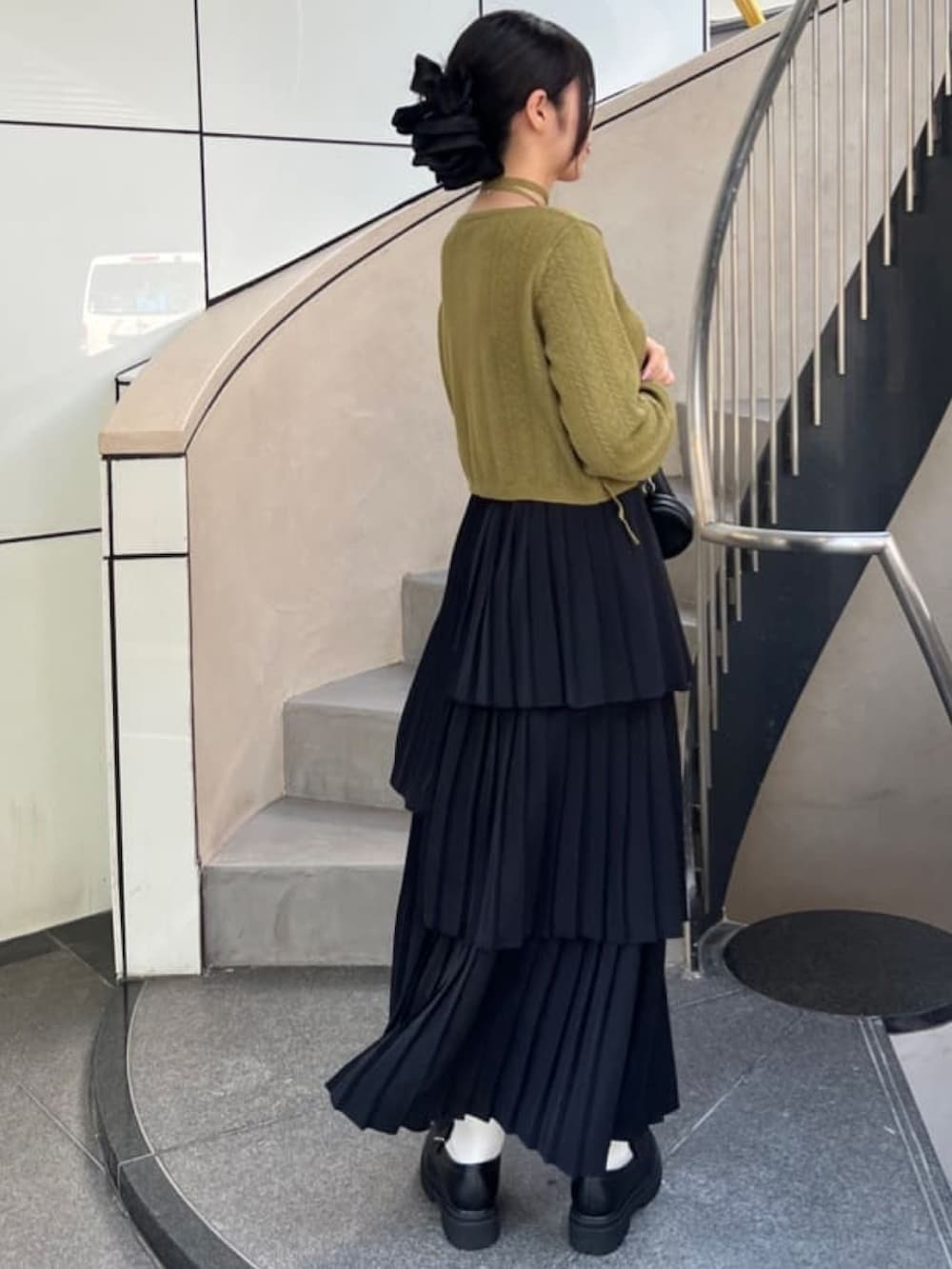 グリーン系のカーディガン/ボレロ、ブラック系のスカートを着用したレディースの秋コーディネートの3枚目の写真