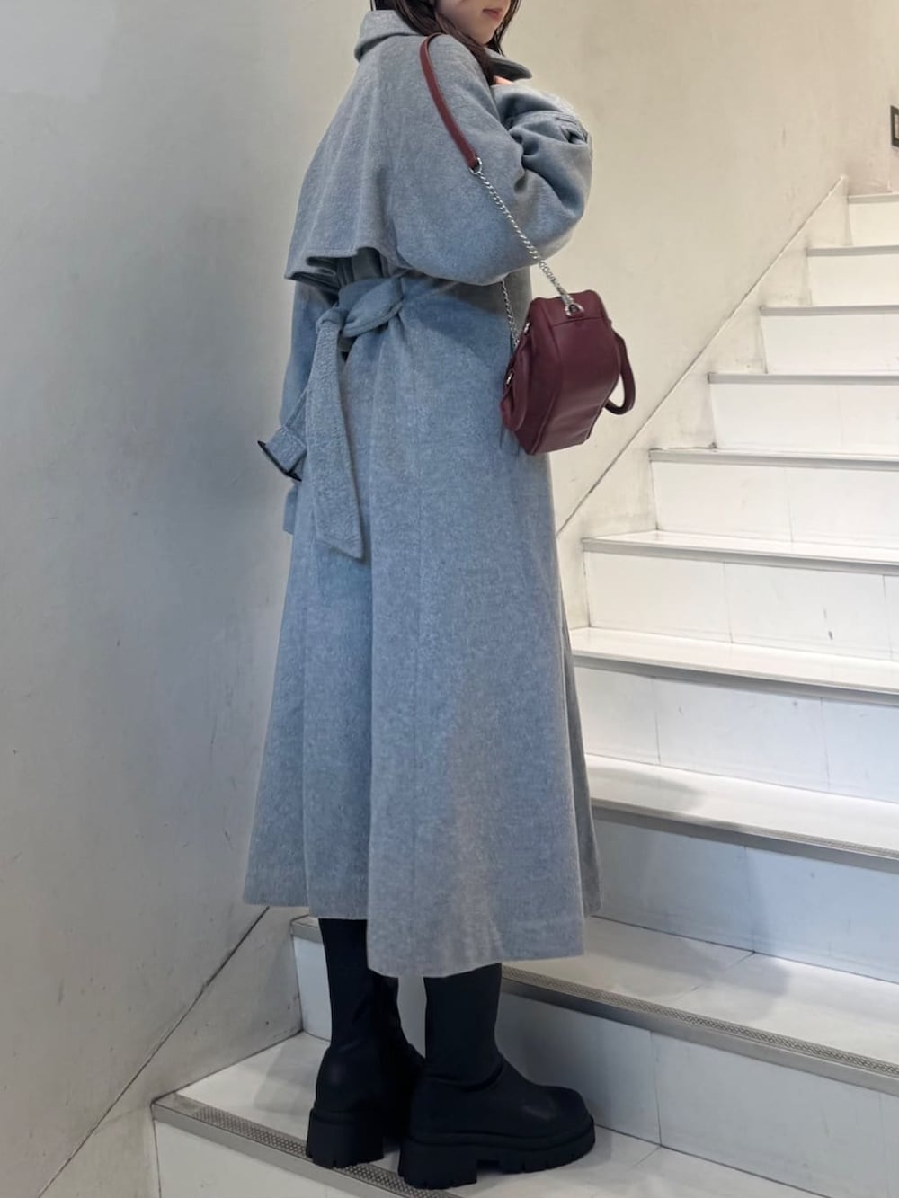 グレー系のトレンチコート、レッド系のショルダーバッグを着用したレディースの秋コーディネートの2枚目の写真