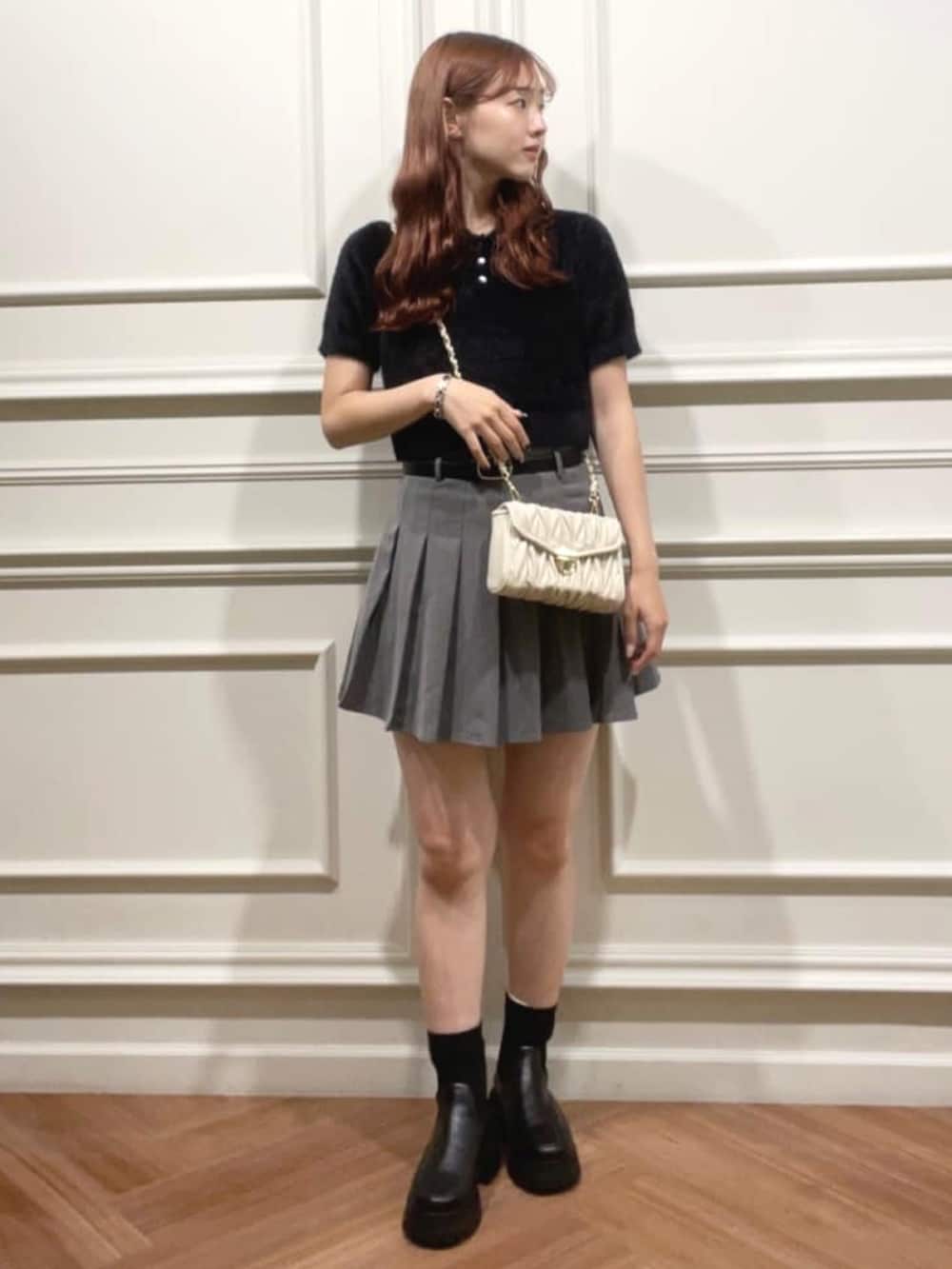 ブラック系のニット/セーター、グレー系のスカート、ホワイト系のショルダーバッグを着用したレディースの夏コーディネートの3枚目の写真