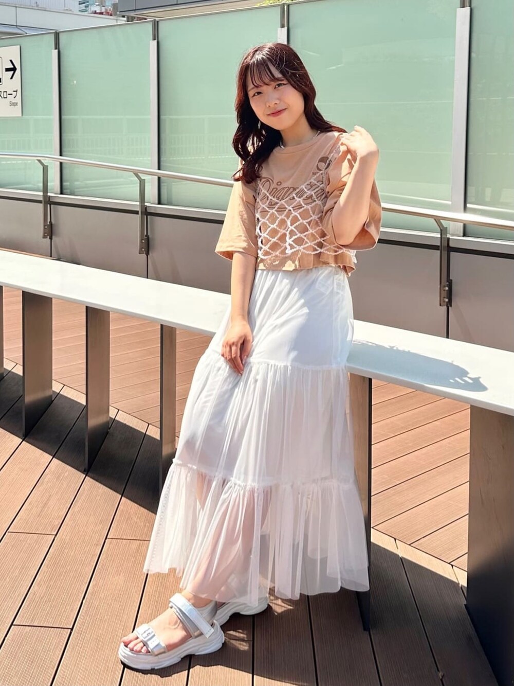 ホワイト系のスカート、ブラック系のサンダル、オレンジ系のTシャツ/カットソーを着用したレディースの夏コーディネートの2枚目の写真