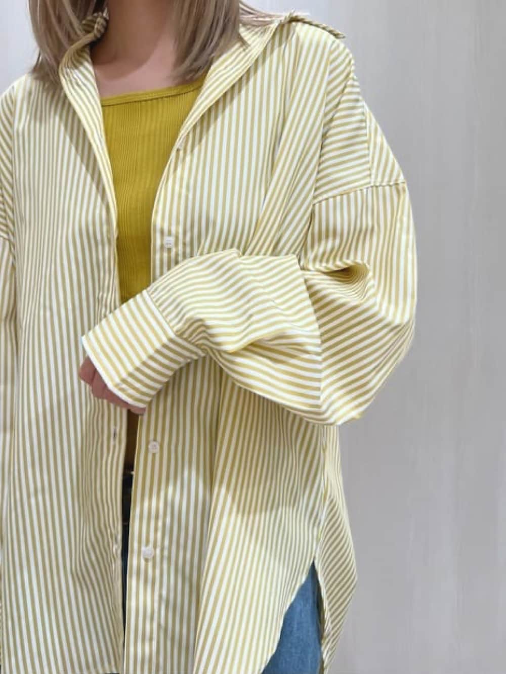 イエロー系のシャツ/ブラウス、イエロー系のタンクトップ、ブルー系のデニムパンツを着用したレディースの春コーディネートの2枚目の写真