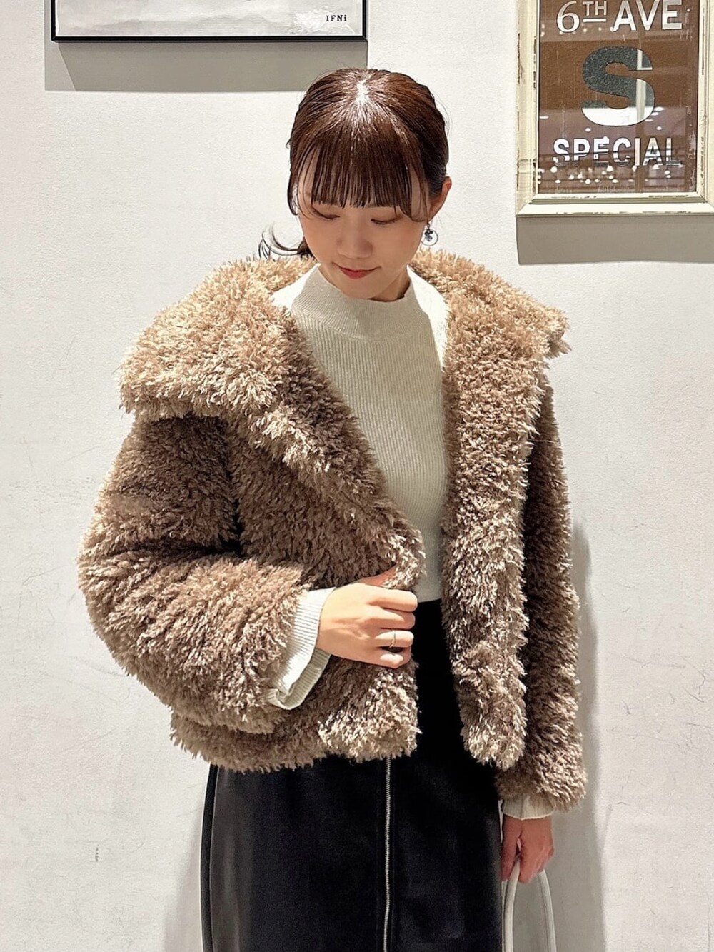 ブラウン系のその他アウター、ホワイト系のニット/セーター、ブラック系のスカートを着用したレディースの冬コーディネートの2枚目の写真