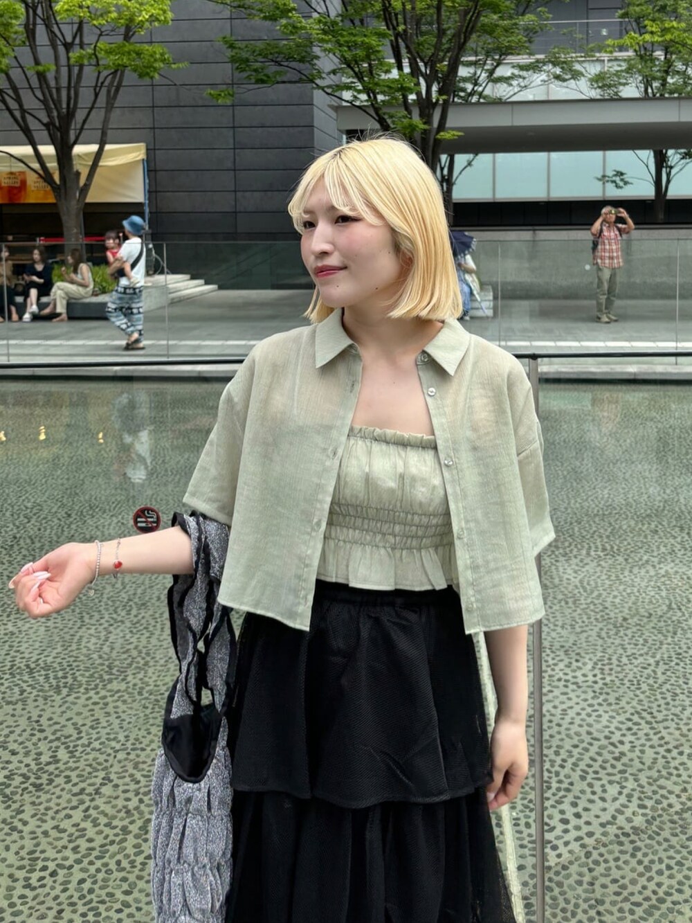 グリーン系のシャツ/ブラウス、ブラック系のスカート、ブラック系のトートバッグを着用したレディースの夏コーディネートの3枚目の写真