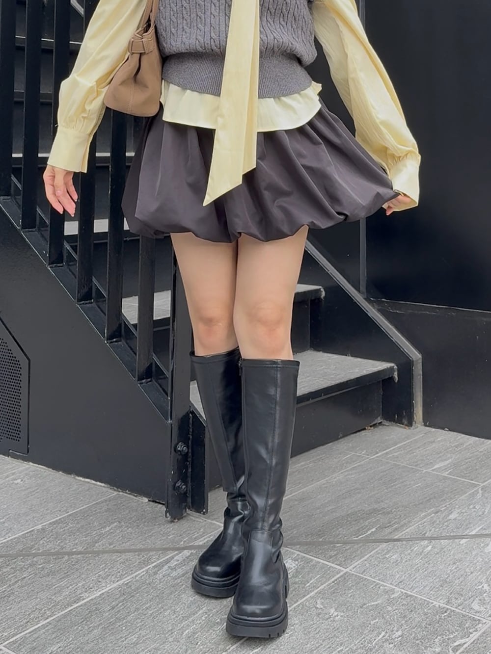 グレー系のニット/セーター、ブラック系のスカートを着用したレディースの秋コーディネートの3枚目の写真