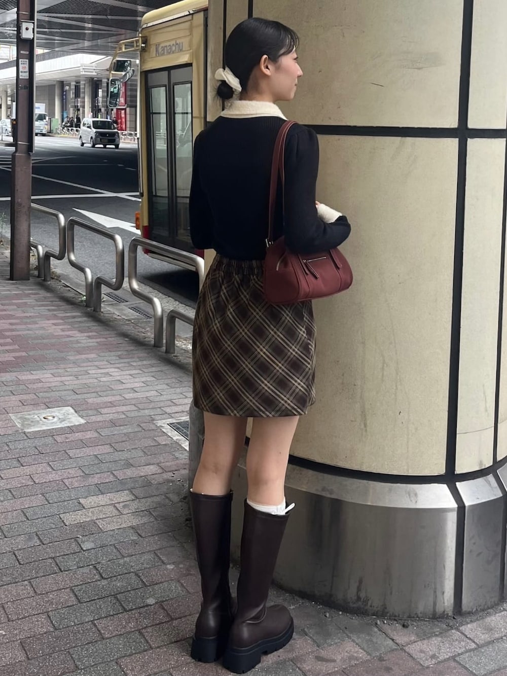 ブラック系のニット/セーター、ブラウン系のスカート、ブラウン系のブーツを着用したレディースの秋コーディネートの3枚目の写真