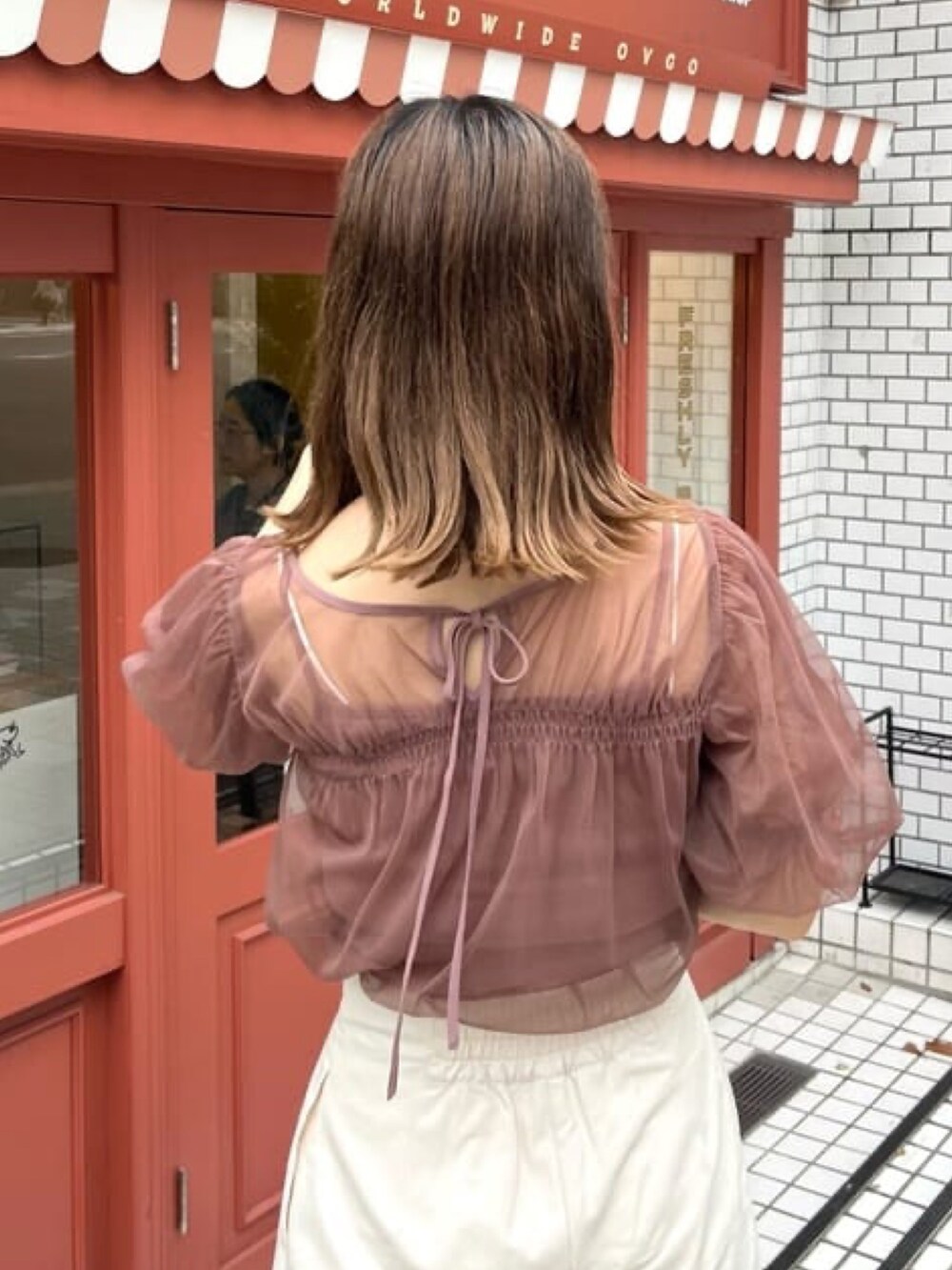 レッド系のTシャツ/カットソー、ホワイト系のスラックス、ホワイト系のショルダーバッグを着用したレディースの夏コーディネートの3枚目の写真