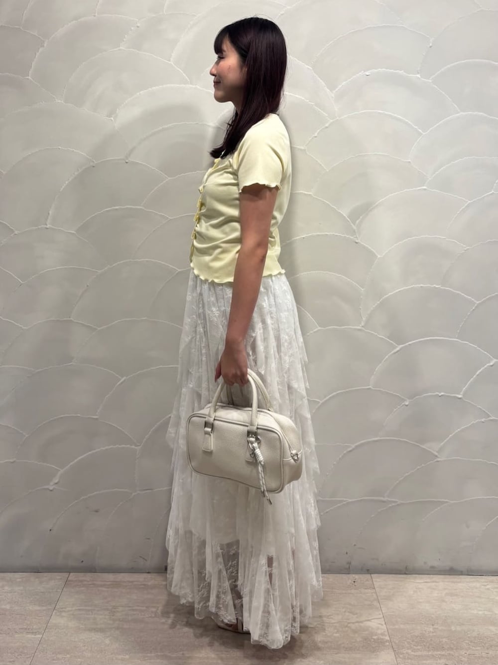 イエロー系のTシャツ/カットソー、ホワイト系のスカート、ホワイト系のボストンバッグを着用したレディースの夏コーディネートの2枚目の写真