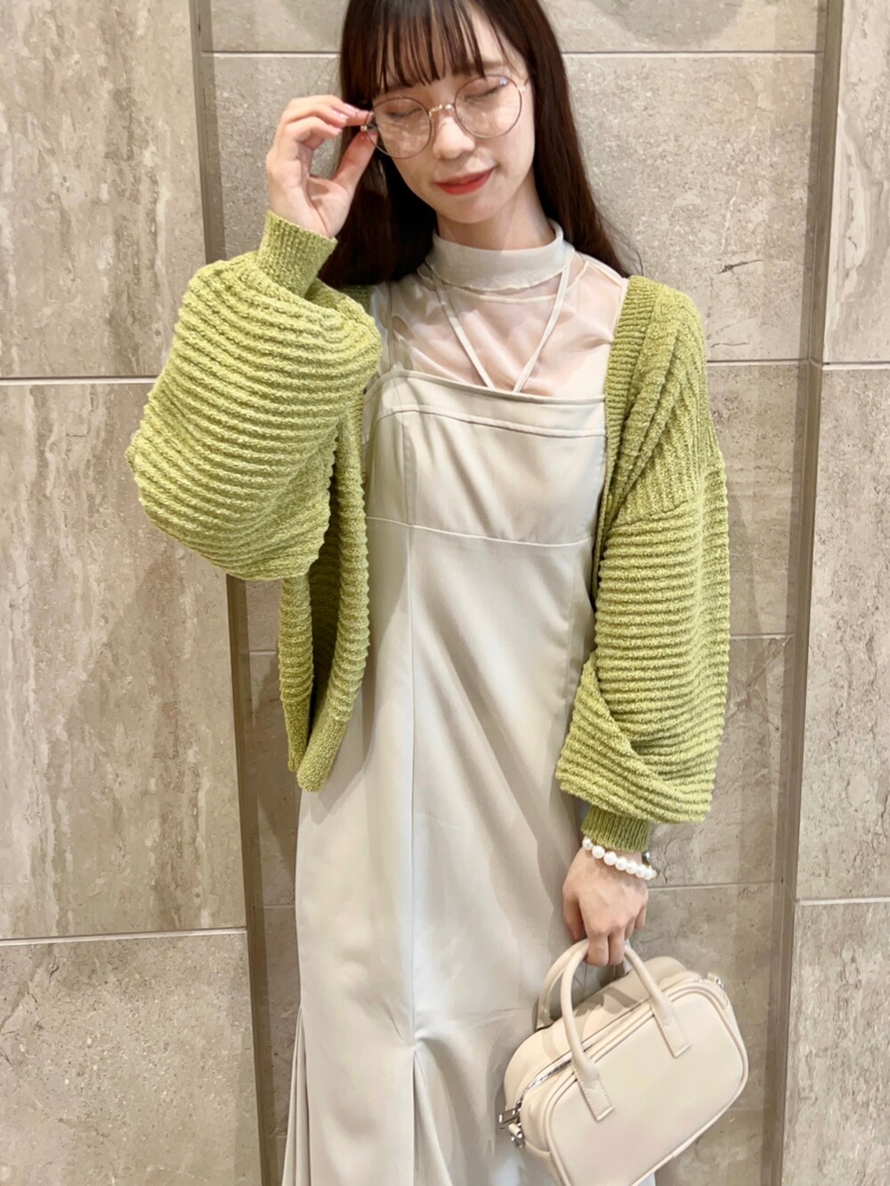 イエロー系のカーディガン/ボレロ、ホワイト系のワンピース、ホワイト系のTシャツ/カットソーを着用したレディースの冬コーディネートの2枚目の写真