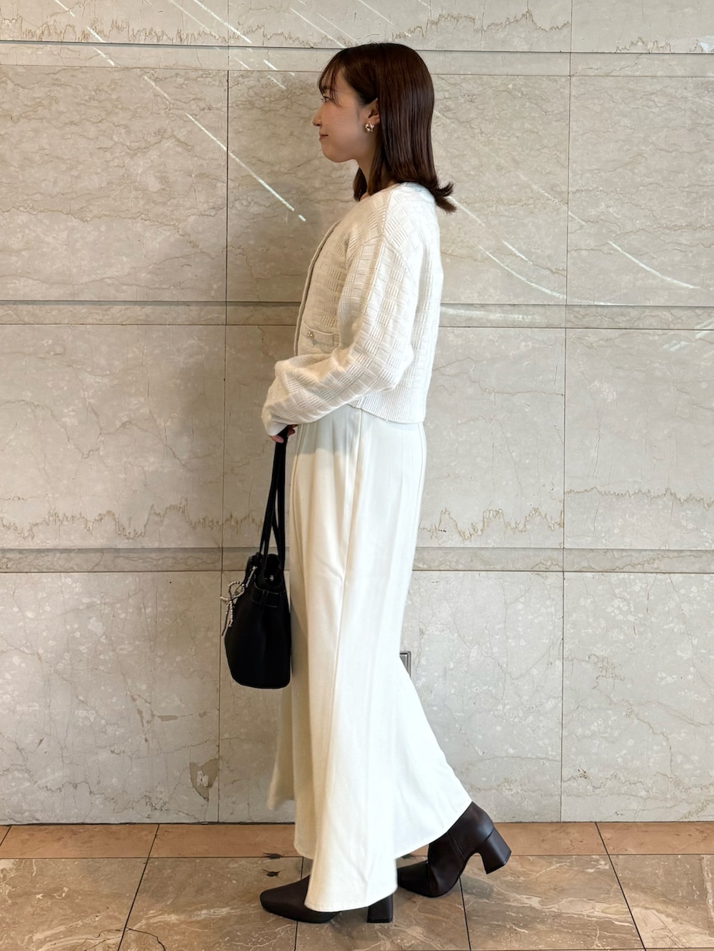 ホワイト系のワンピース、ブラック系のブーツ、ブラック系のショルダーバッグを着用したレディースの秋コーディネートの2枚目の写真